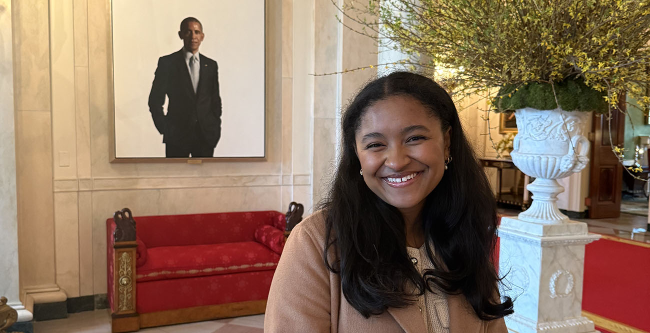 Raja Bella Hicks in Washington, DC posing in front of a portrait of Obama