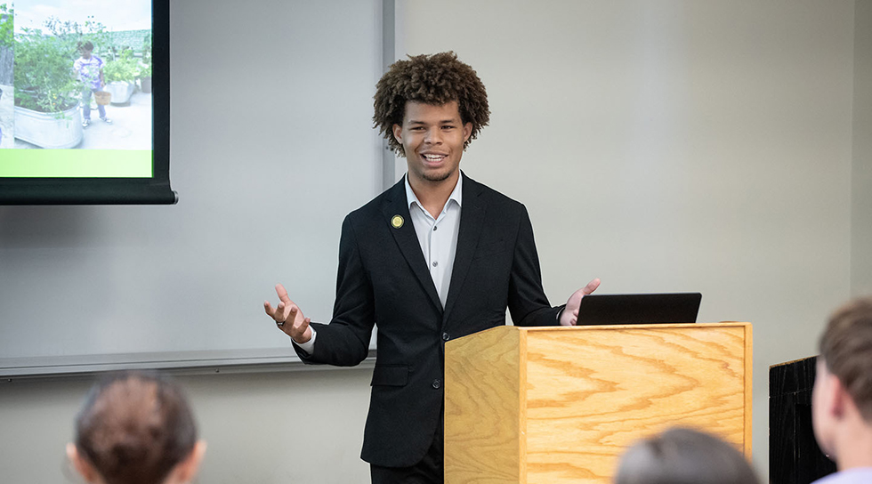 Jaymes Griggs presenting at a lectern at the Summer Research Program conference on the Occidental campus.